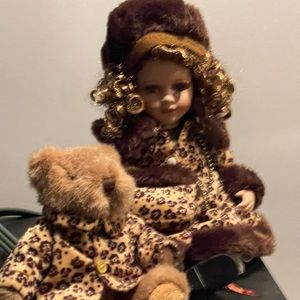 Leopard wearing porcelain doll with teddy bear